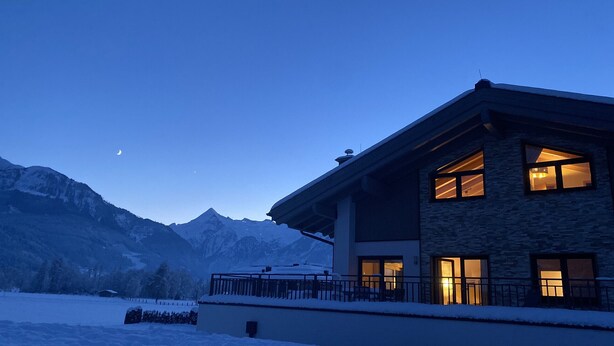 A two-story house with large windows and a balcony, surrounded by snow-covered mountains. - Kitzview Terrace Apartment (Zell am See)