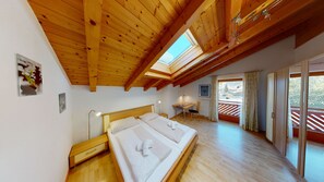 Relax in this inviting bedroom with a large bed, bedside table, and desk offering a view of the outdoors.