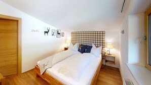 A neatly made bed with a checkered headboard, two bedside lamps, and wall art featuring animal silhouettes.