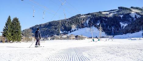 Pista de esquí con telesillas, terreno cubierto de nieve y una montaña al fondo.