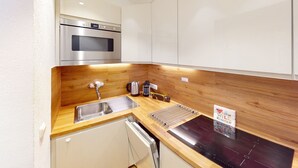A compact kitchen with a stainless steel oven, a sink, and a wooden countertop.