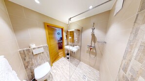 A modern bathroom with a glass-enclosed shower, a white sink, and a toilet.