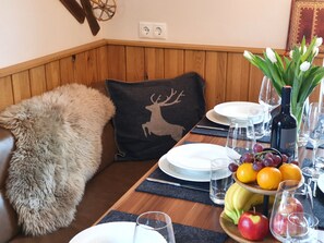 A dining table set with plates, glasses, a bottle of wine, and a fruit bowl.