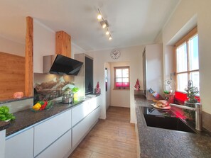 A modern kitchen with a central island, wooden accents, and a window with a view.