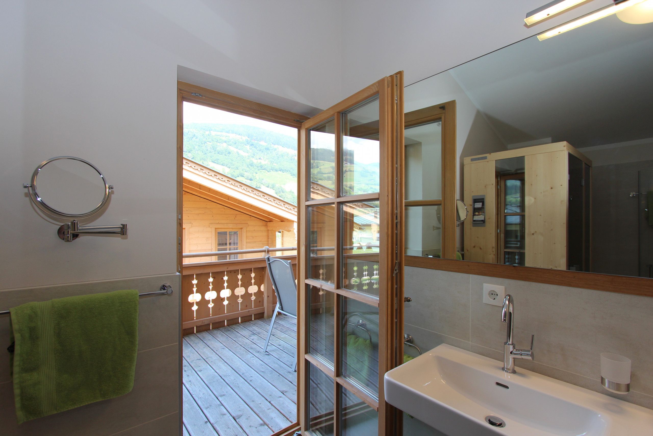 A bathroom with a wooden deck, a green towel, a sink, and a mirror.