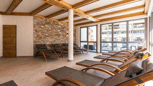 A sunlit room with wooden beams, stone walls, and multiple wooden chairs with cushions. - SPA Apartments Comfort Studio 102 (Zell am See)