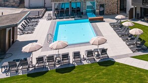 A modern hotel with a swimming pool, outdoor seating, and a view of the surrounding hills. - SPA Apartments Comfort Studio 102 (Zell am See)