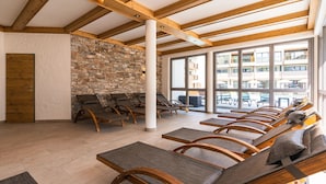 A sunlit room with wooden beams, stone walls, and multiple wooden chairs with cushions. - SPA Apartments Comfort Studio 103 (Zell am See)