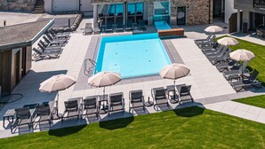 A modern hotel with a swimming pool, outdoor seating, and a view of the surrounding hills. - SPA Apartments Comfort Studio 103 (Zell am See)