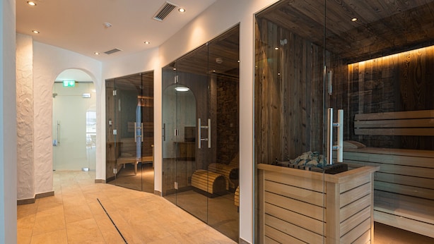 A modern spa area with glass walls, wooden benches, and a reception desk. - SPA Apartments Comfort Studio 103 (Zell am See)