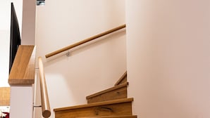 Un escalier en bois, doté d’une rampe, menant à un palier avec une surface plane.