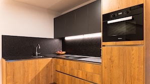 Une cuisine moderne avec des meubles en bois, un plan de travail noir et un four encastré.