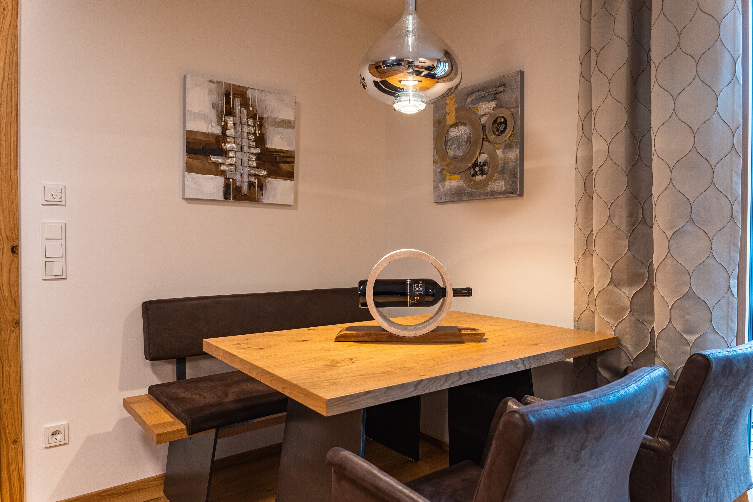 Comedor con mesa de madera, bancos y una lámpara colgante.