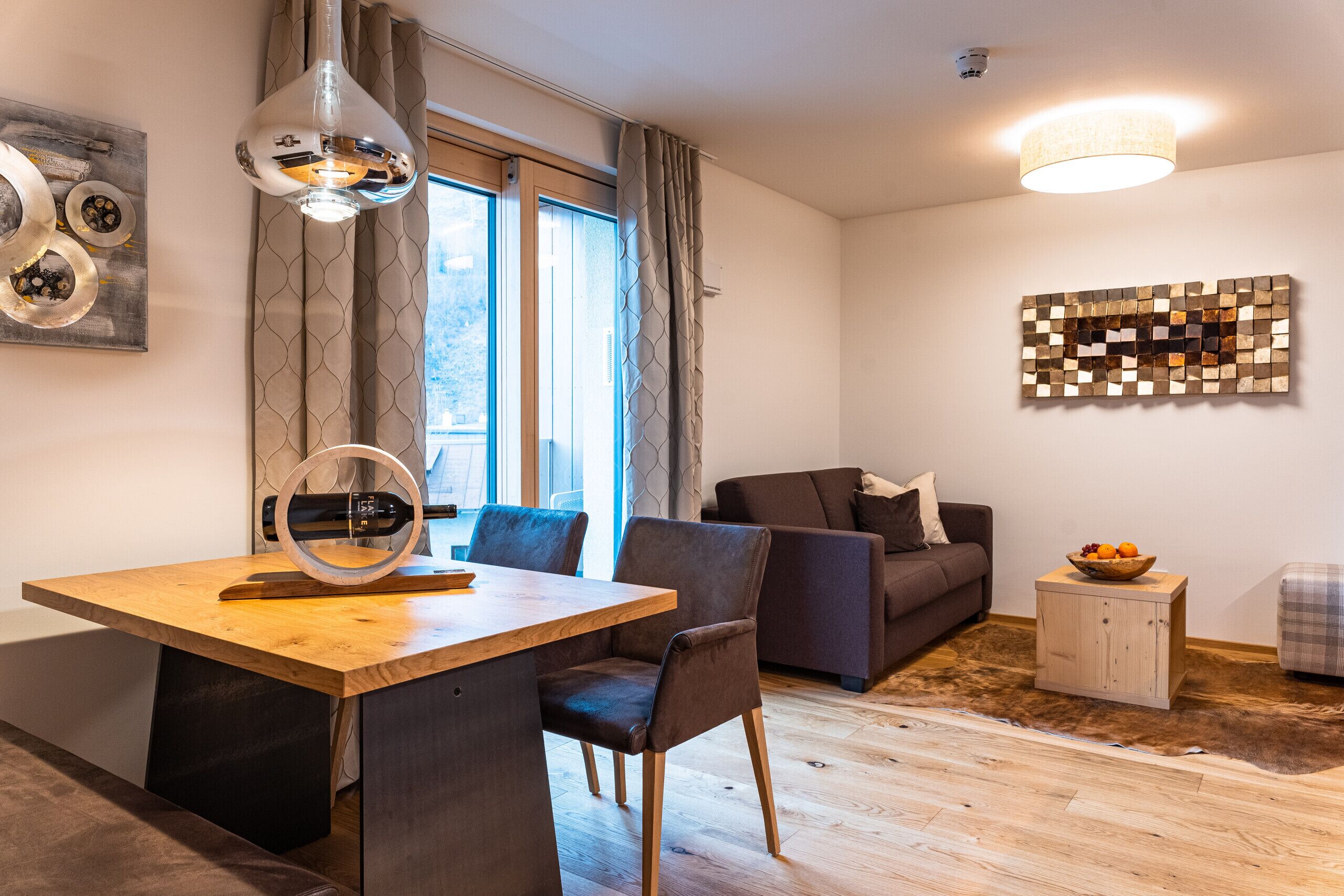 Una sala de estar moderna con una mesa de comedor de madera, un sofá y una pequeña mesita auxiliar con un frutero.