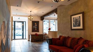 A lobby with a red sofa, a chandelier, and a painting on the wall. - SPA Apartments Junior Suite 208 (Zell am See)