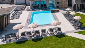 A modern hotel with a swimming pool, outdoor seating, and a view of the surrounding hills. - SPA Apartments Junior Suite 208 (Zell am See)