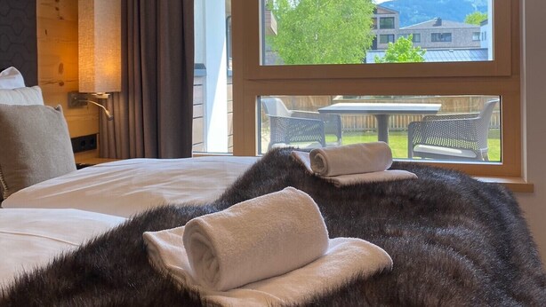 Ein Hotelzimmer mit einem großen Bett, Blick ins Freie und einem Vorhangfenster.