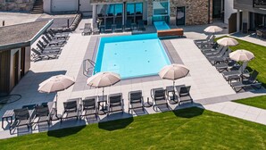 Un hotel modern amb una piscina, zones d'estar a l'aire lliure i vistes als turons del voltant.