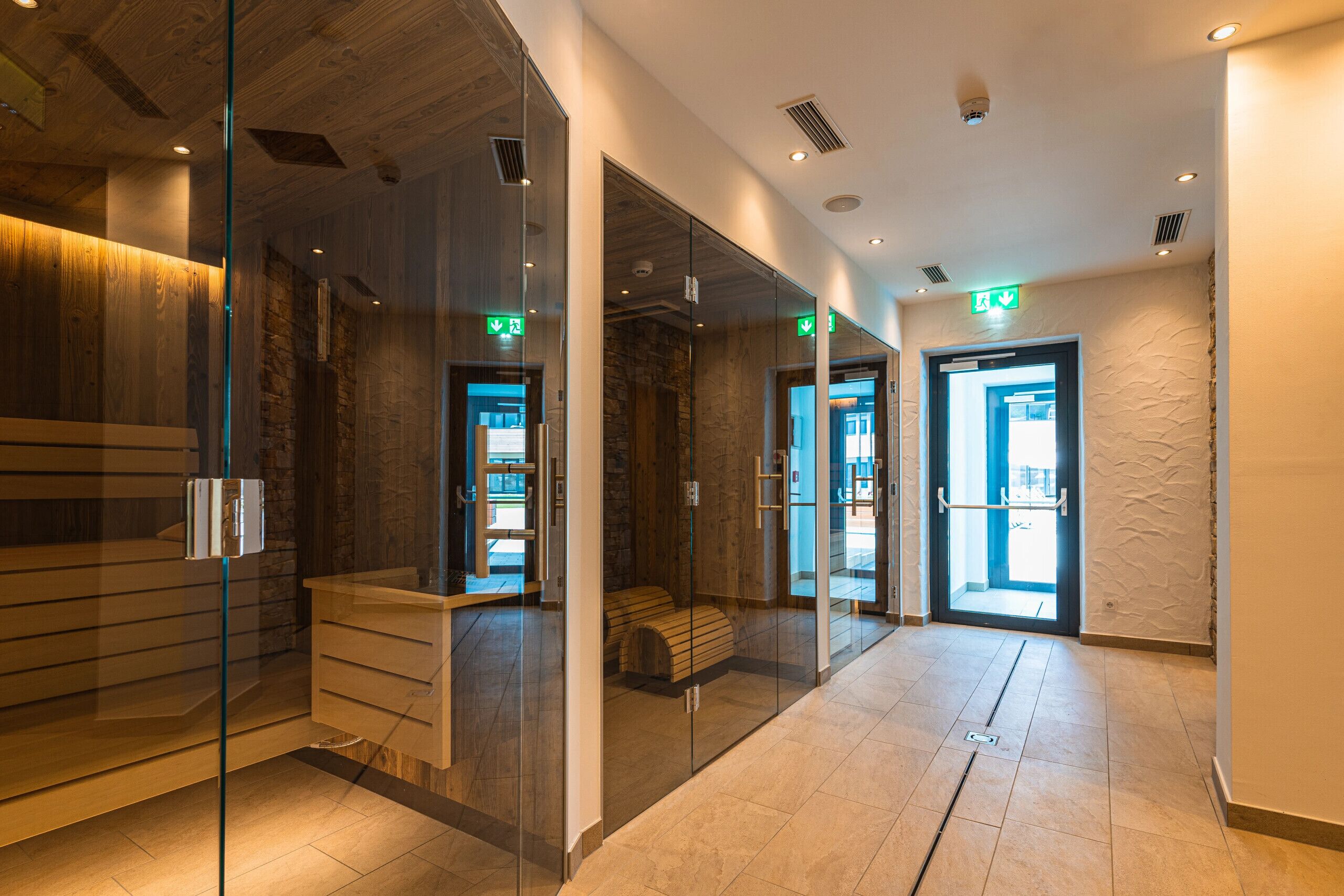 Un moderno hall de hotel con un panel de vidrio, paneles de madera y un mostrador de recepción.