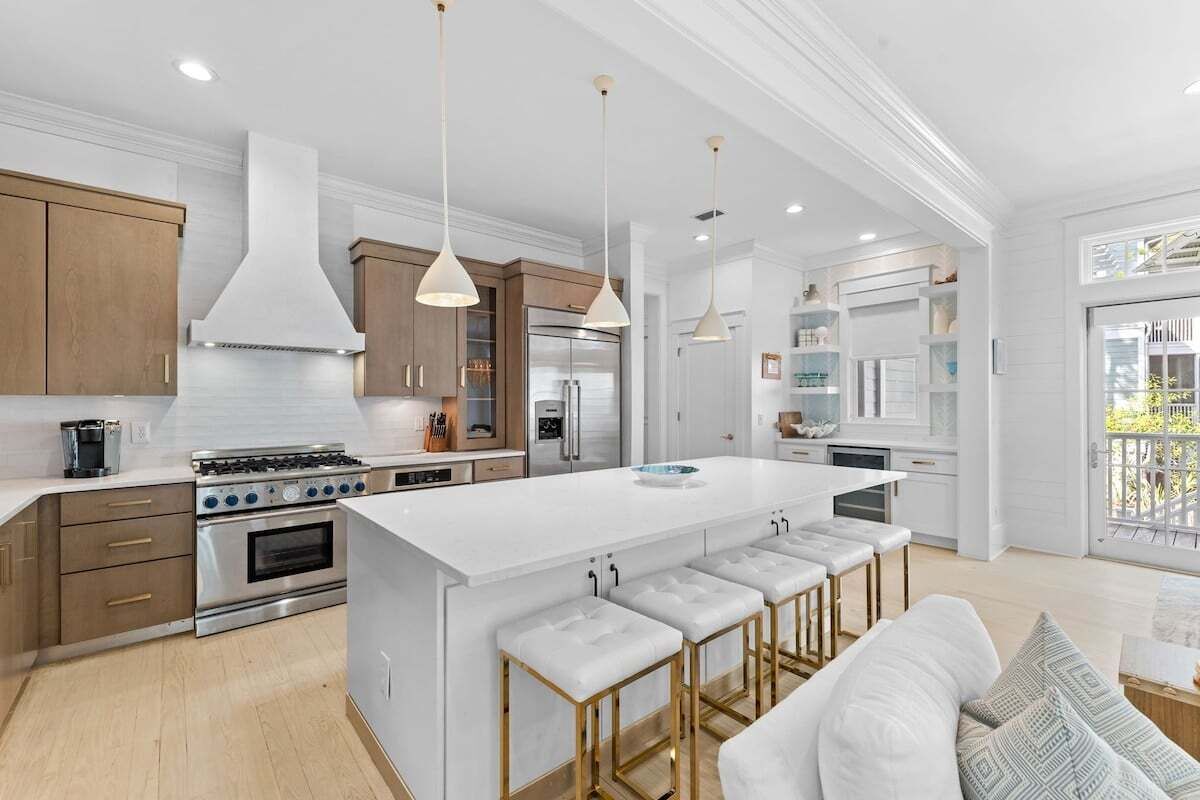 A modern kitchen with a large island, stainless steel appliances, and pendant lighting.