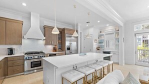 A modern kitchen with a large island, stainless steel appliances, and pendant lighting. - WaterColor! Carriage House, Pool, LSV, Bikes! Next to Camp WaterColor Waterpark! (Santa Rosa Beach)