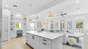 A spacious kitchen with white cabinetry, a large island, pendant lighting, and a ceiling fan. - WaterColor! Carriage House, Pool, LSV, Bikes! Next to Camp WaterColor Waterpark! (Santa Rosa Beach)