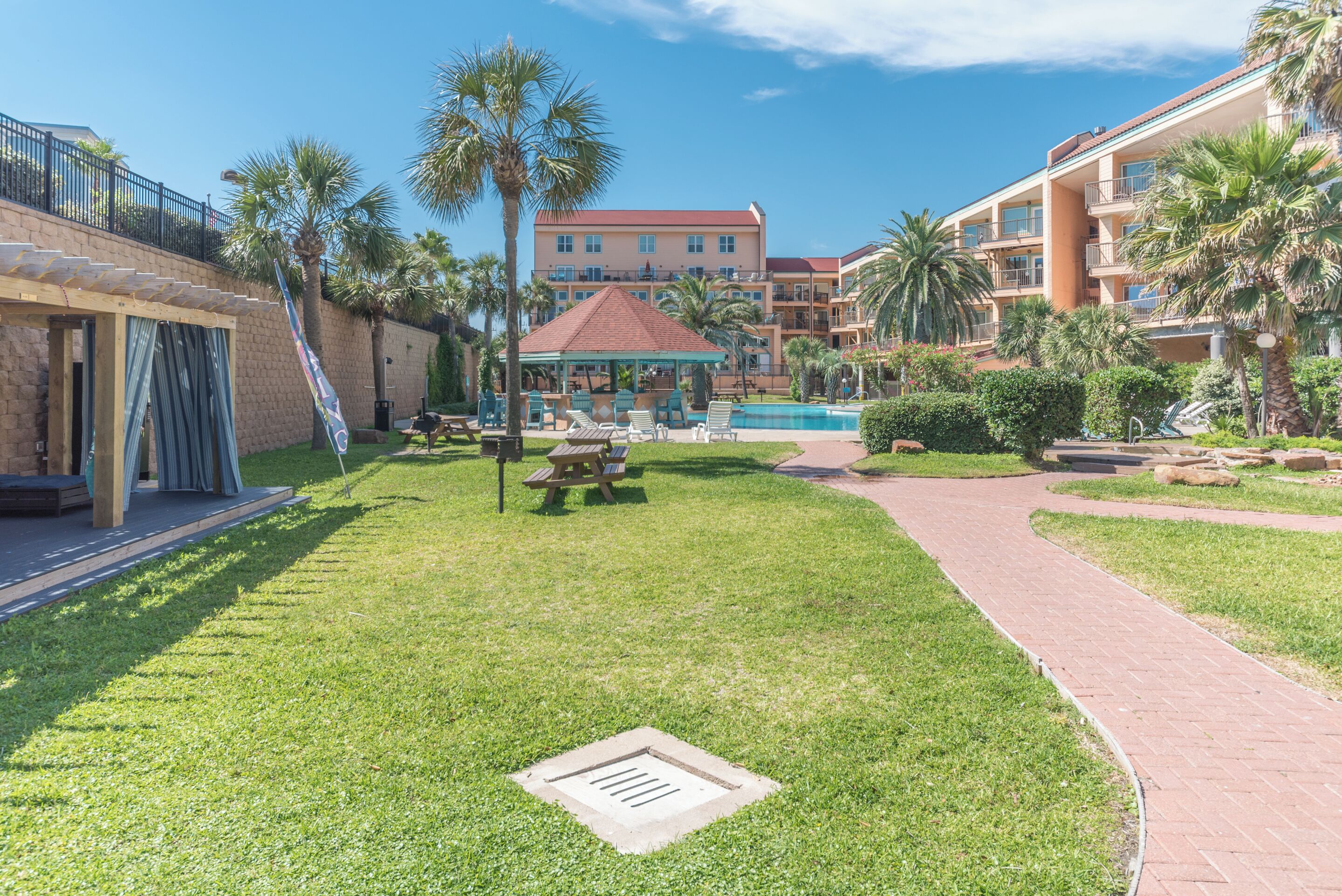 Une cour d’hôtel avec une piscine, des palmiers et un kiosque.