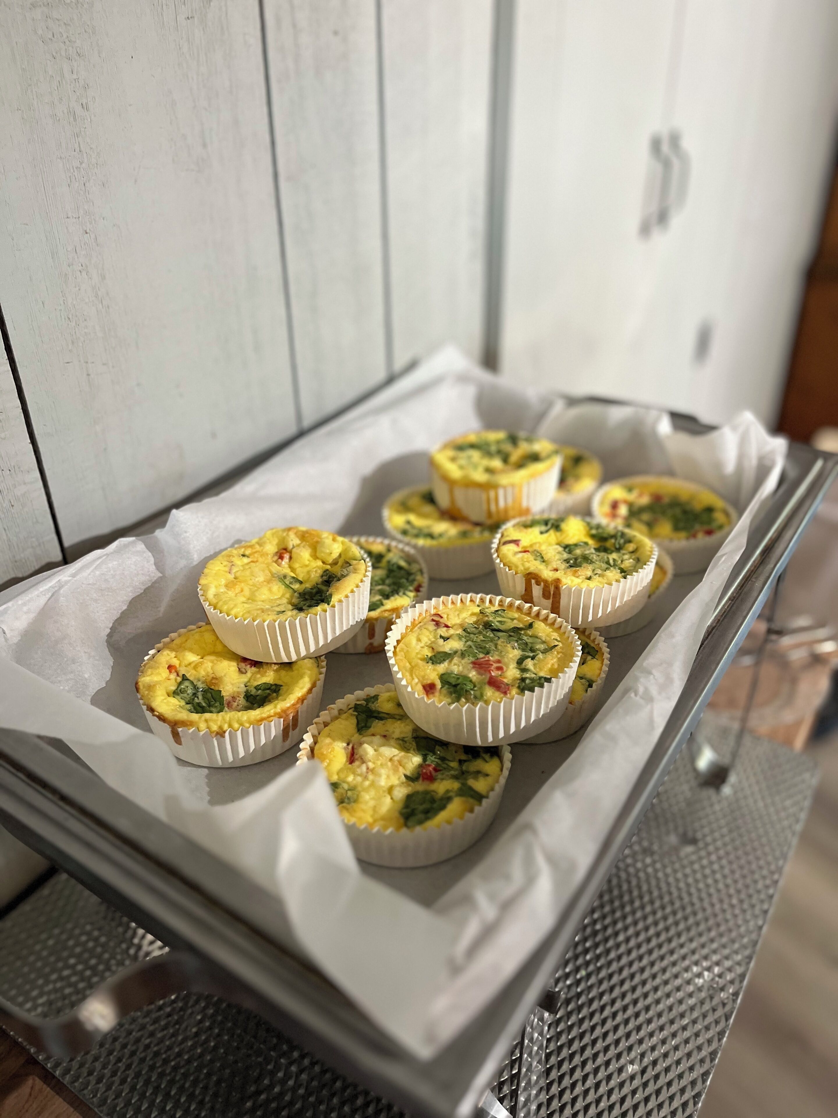 A tray of quiches on parchment paper in a kitchen setting.