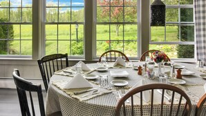A dining table set for four with a view of a garden through large windows. - COHO Inn & Motor Lodge (Weston)
