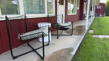 A porch with two metal chairs and a small table.