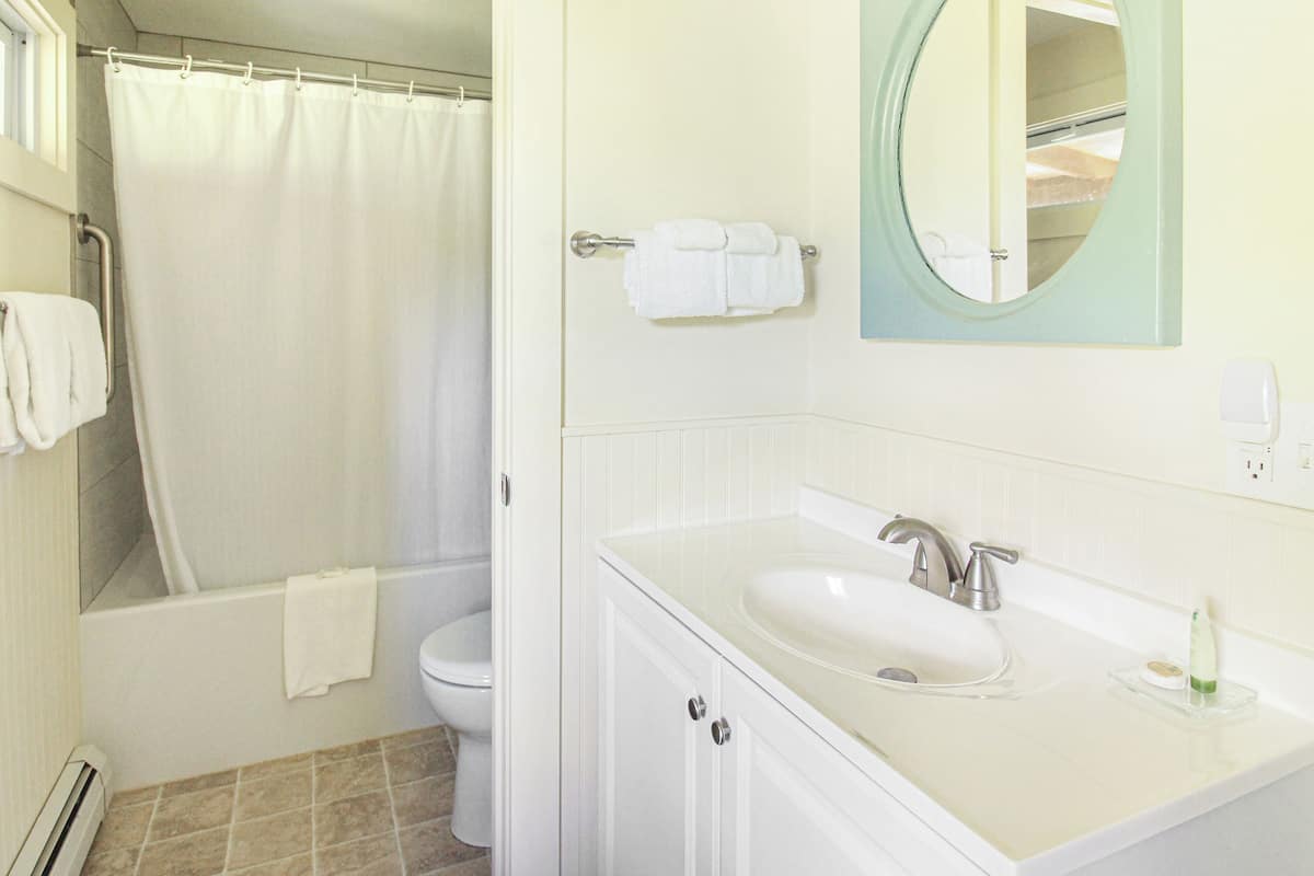 A bathroom with a bathtub, toilet, sink, and a mirror.