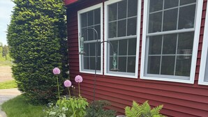 A house with a red exterior, large windows, and a well-maintained garden with various plants and flowers. - COHO Inn & Motor Lodge (Weston)