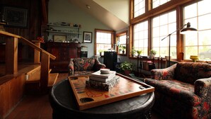 A cozy living room with a fireplace, wooden furniture, and large windows. - COHO Inn & Motor Lodge (Weston)