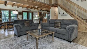 Ein geräumiges Wohnzimmer mit einem großen, grauen Sofa, einem Couchtisch und einer Holztreppe.