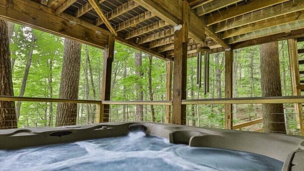 Ein Whirlpool mit Holzkonstruktion und Blick auf einen Wald.