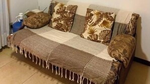 A living room with a sofa, a painting on the wall, and a small table with a cup. - Stunning 2-bed Apartment in Pipa Beach (Tibau do Sul)