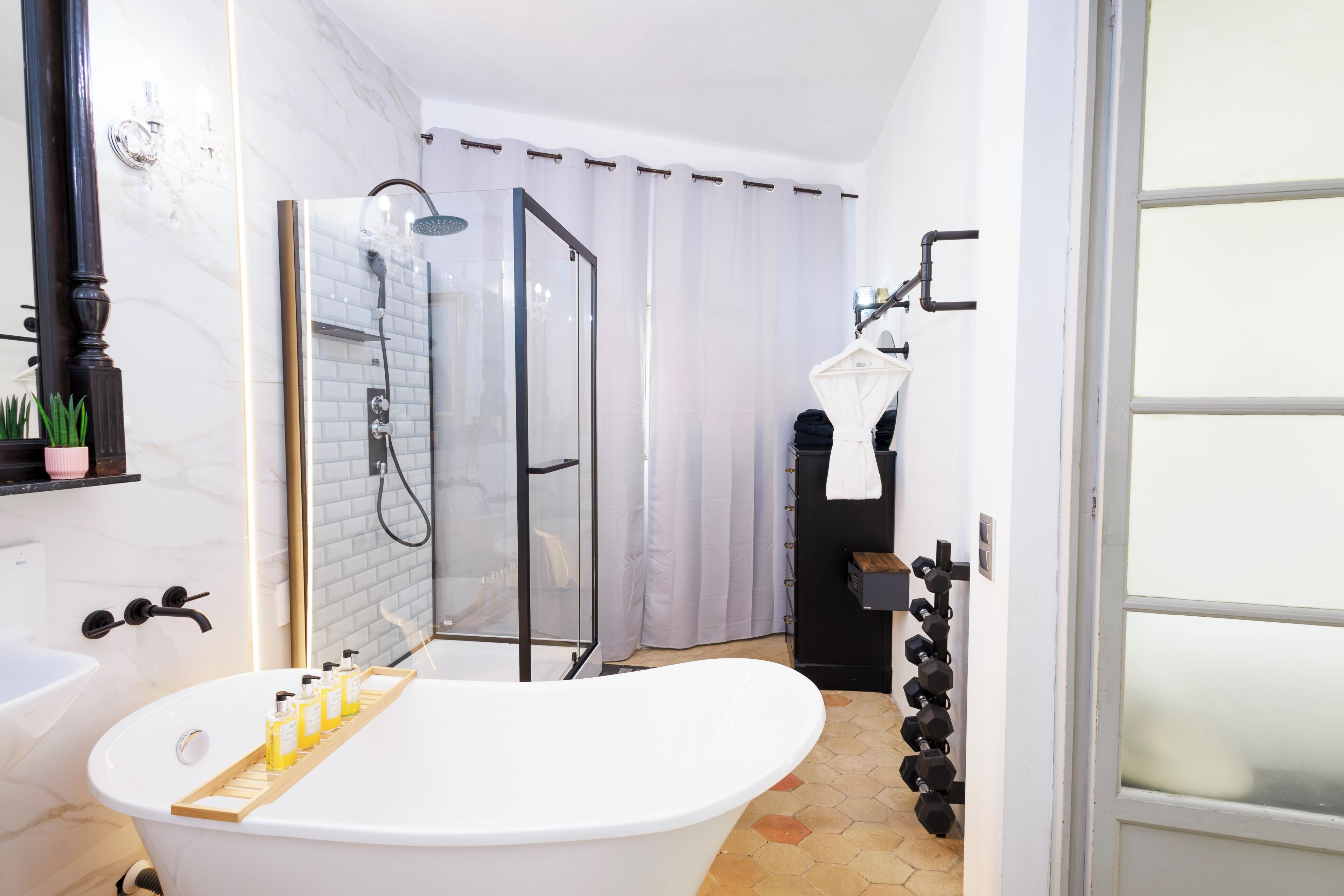 Baño con bañera, ducha y mampara de vidrio.
