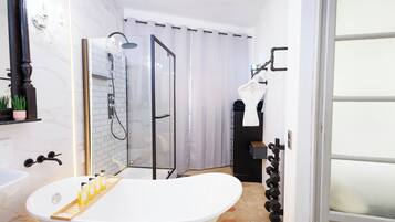 Baño con bañera, ducha y mampara de vidrio.