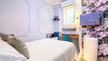 Een slaapkamer met een bed, een bureau, een stoel, een radiator en een aan de muur bevestigde televisie.