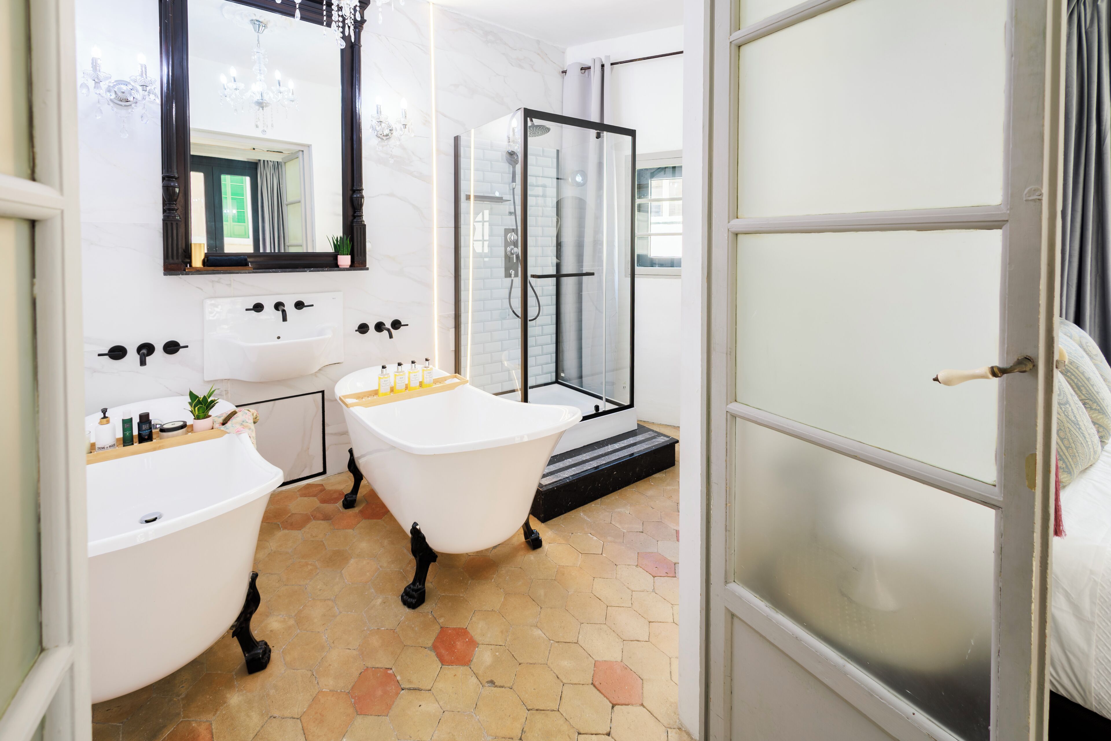 A bathroom with a clawfoot bathtub, a glass-enclosed shower, and a double sink.