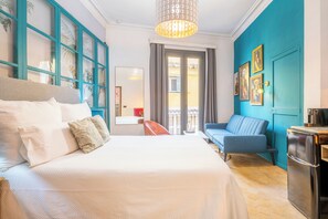 A hotel room with a bed, a sofa, a dining area, and a kitchen.