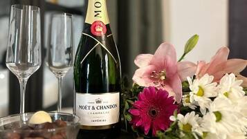 Pullo Moët & Chandon -samppanjaa, kaksi lasia ja kukkakimppu pöydällä.