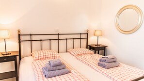A double bed with a headboard, two bedside tables, a lamp on each table, and a mirror on the wall.