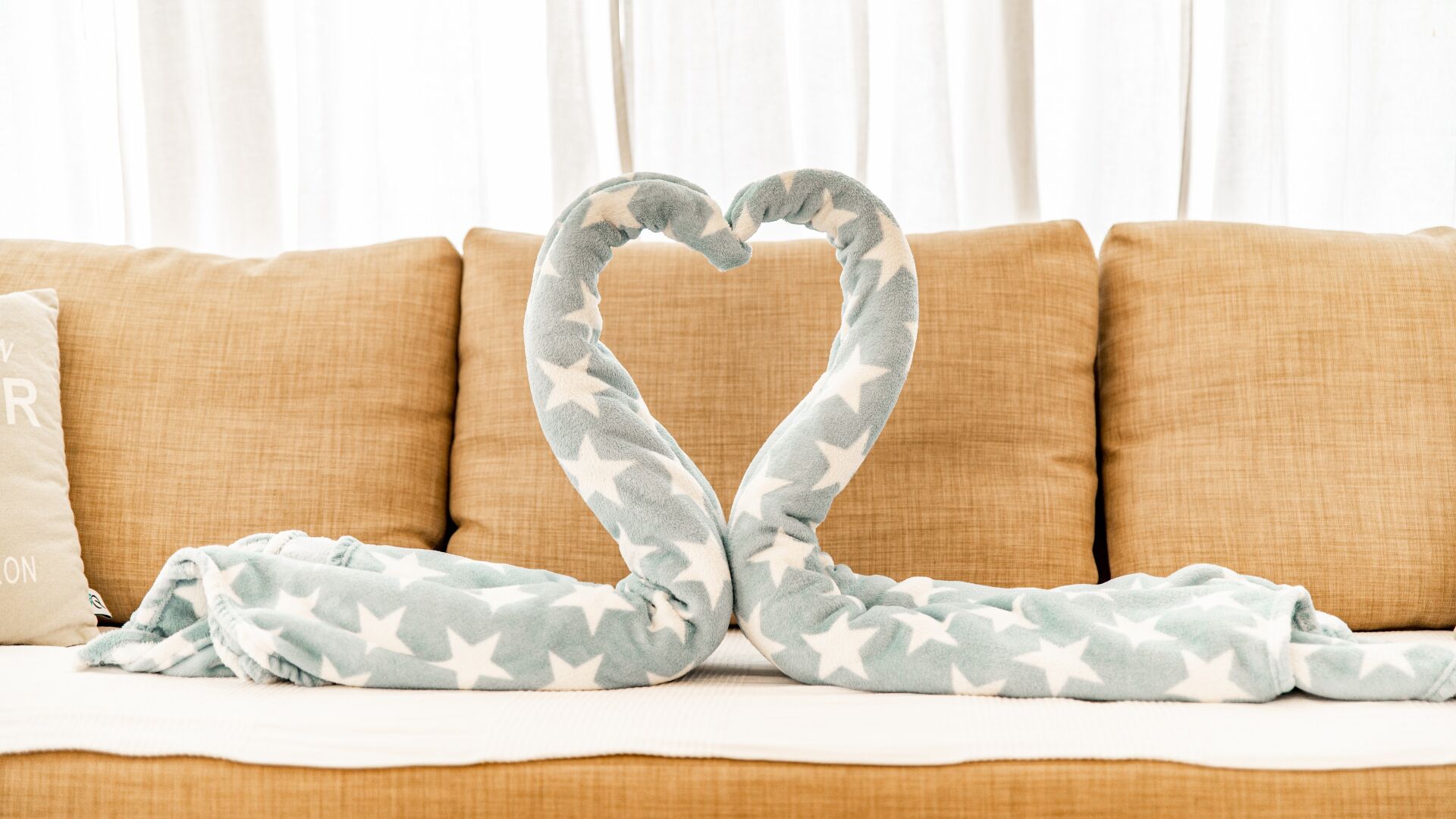 A couch with a heart-shaped arrangement of a blanket.