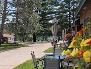 A patio area with outdoor seating, a small building, and a view of a body of water.