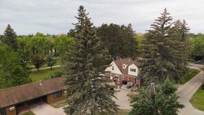 A two-story house with a brick exterior, a covered patio, and a driveway. - Brick House on the River at Riverside Point Resort (Park Rapids)