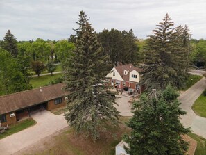 Une maison à deux étages avec une façade en briques, un patio couvert et une allée.