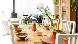 Un comedor con una mesa dispuesta para una comida, rodeado de sillas blancas.