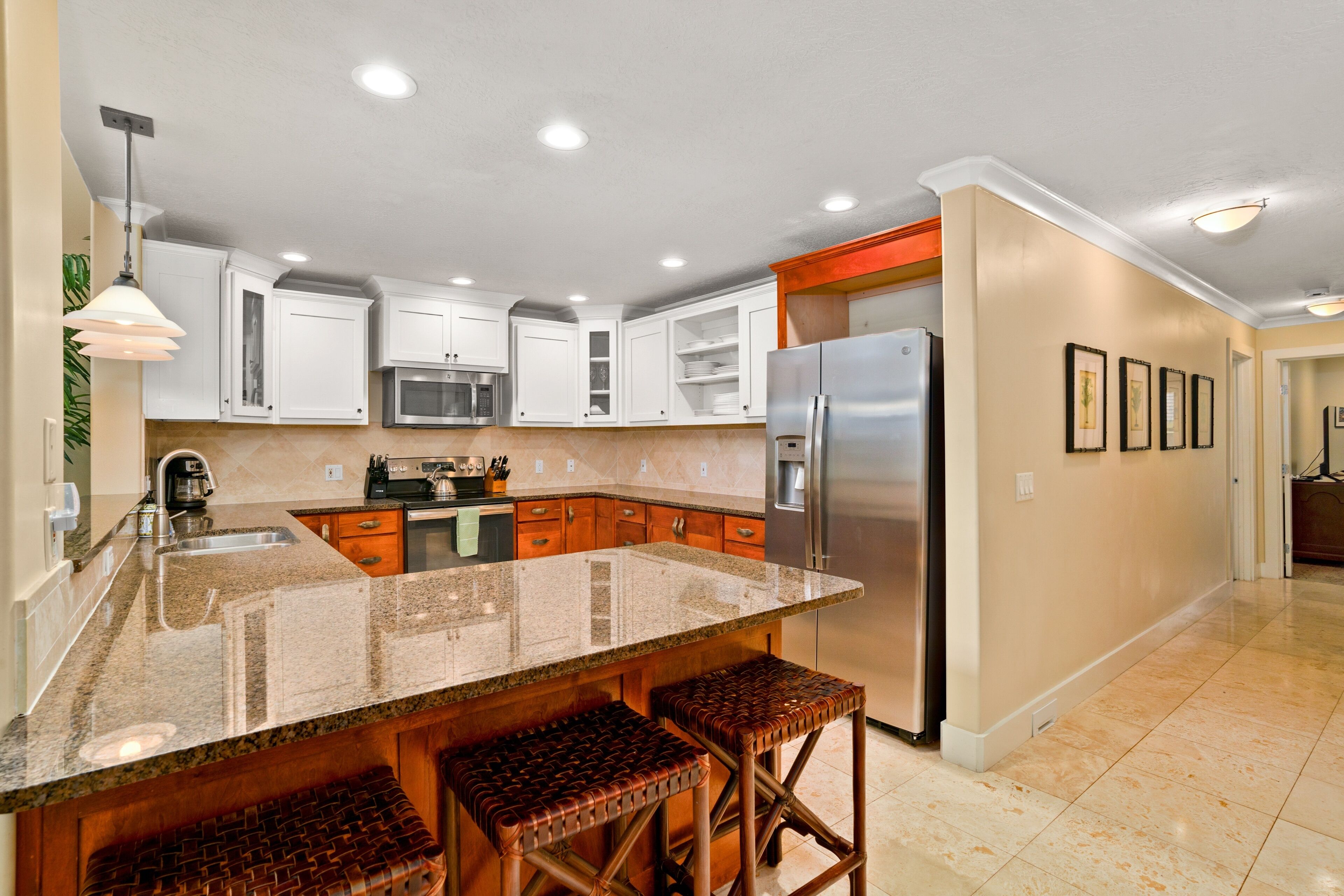 A modern kitchen with white cabinets, a stainless steel refrigerator, and a granite countertop.