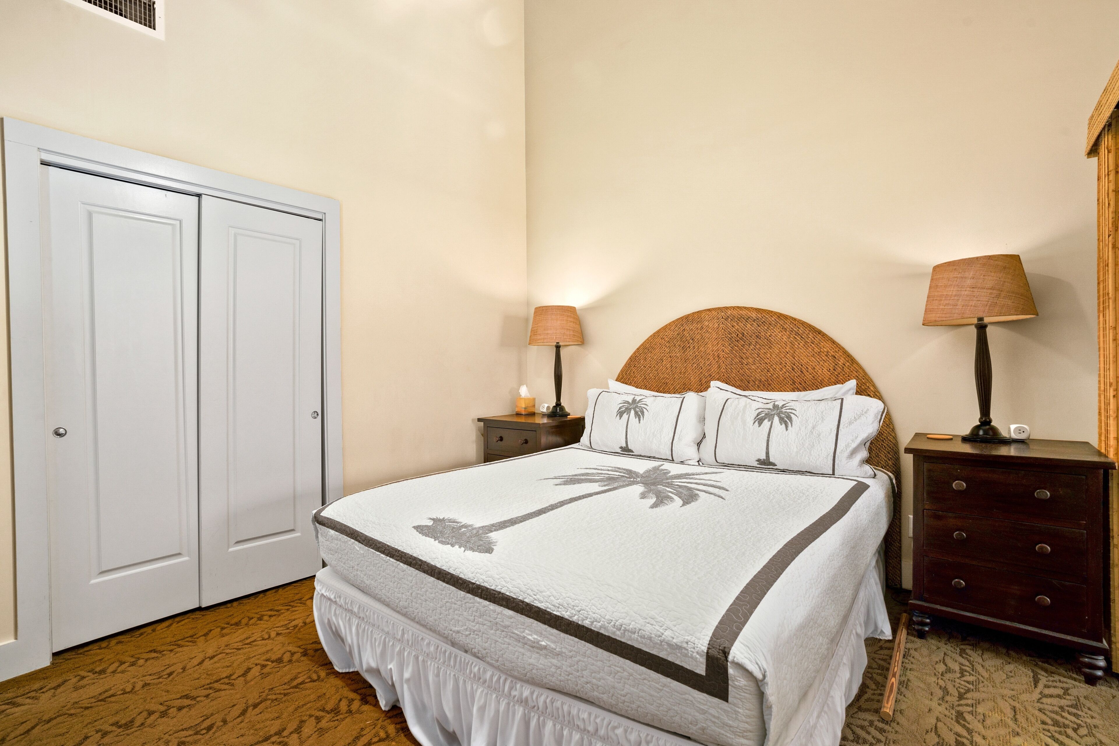 Une chambre à coucher avec un lit, deux tables de chevet, une armoire et une lampe.